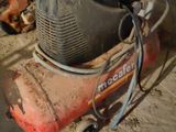 a small air compressor sitting on the ground in a garage