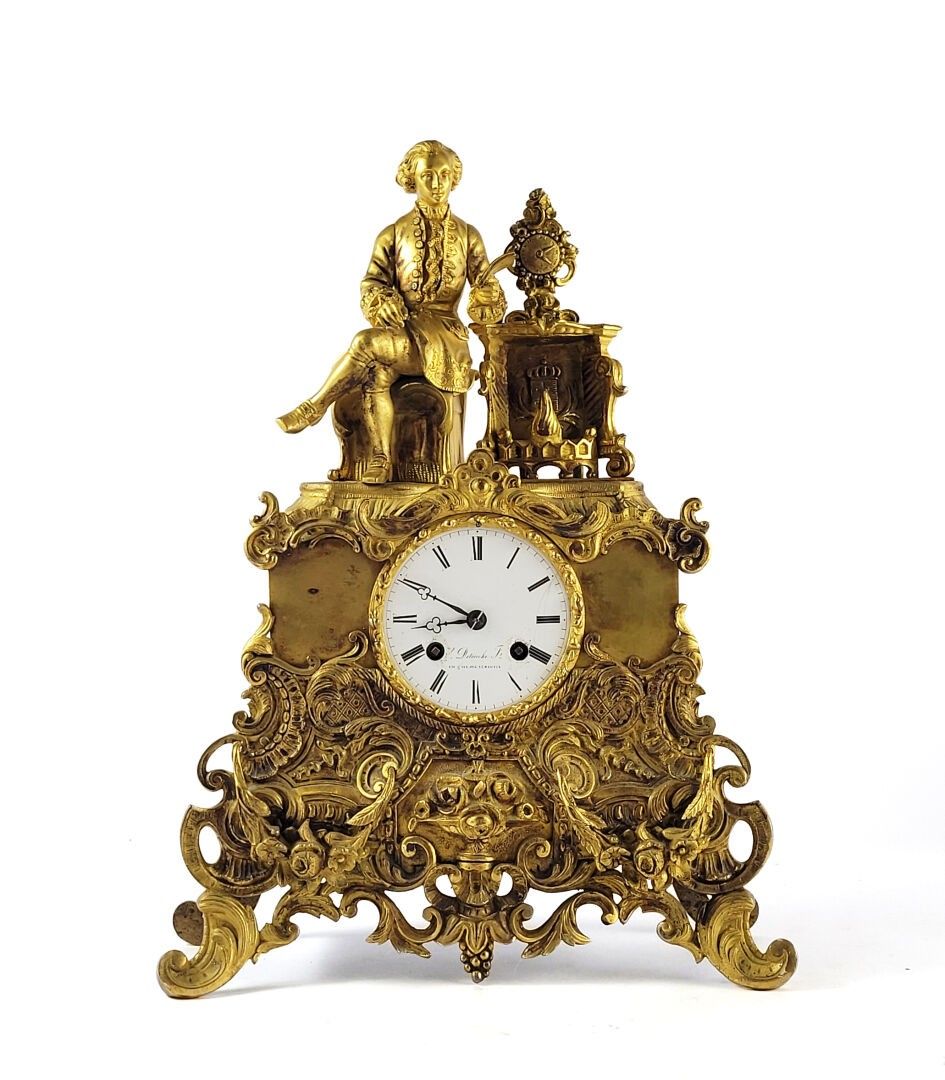 PENDULE en bronze doré à décor d'une homme à l'habit ancien régime, à la lecture près d'une cheminée. Le cadran à chi...
