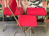 three red chairs sitting next to each other in front of a wall