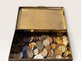 a small metal box filled with coins on a white surface