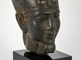 une tête d'homme en bronze coiffée d'un chapeau, posée sur un socle noir