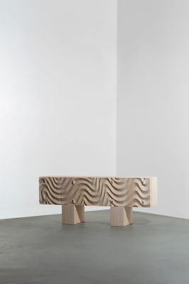 un banc en bois posé sur un sol en béton, près d'un mur blanc