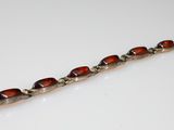 a close up of a silver bracelet with red beads on a white surface
