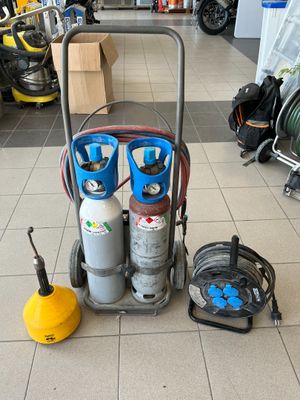 un chariot avec des bouteilles de gaz et des tuyaux posé par terre