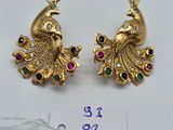 une paire de boucles d'oreilles en or en forme de paon, ornées de pierres multicolores