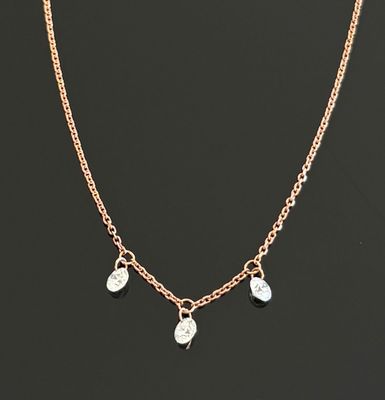 un collier à chaîne en or orné de trois breloques sur fond noir