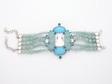 a close up of a bracelet with blue beads and a white stone