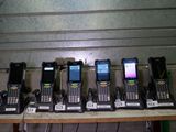 Plusieurs téléphones portables sont alignés sur une table devant un mur.