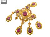 un gros plan sur un collier et des boucles d'oreilles en or sertis de pierres rouges
