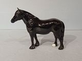 figurine of a black horse standing on a white surface