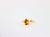 un gros plan d'une bague sertie d'un saphir jaune sur une surface blanche