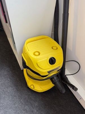 un aspirateur jaune posé par terre près d'un mur blanc