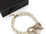 a close up of a bracelet with pearls and a bow