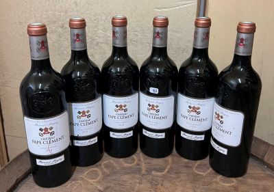 six bouteilles de vin rouge sont alignées sur un tonneau en bois