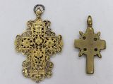 two gold crosses are sitting next to each other on a white surface