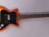 une guitare électrique orange et noire posée sur une surface blanche