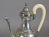 a silver tea pot with a handle on a table