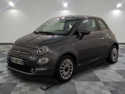La petite voiture grise est garée dans le garage, sur le sol à damier.
