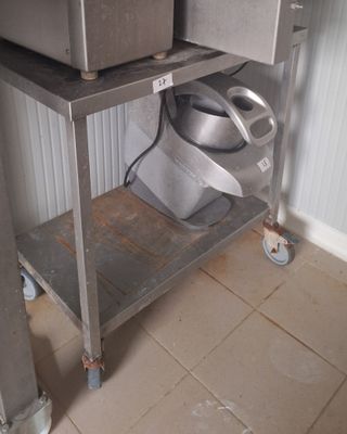 un micro-ondes argenté posé sur une étagère métallique à côté des toilettes