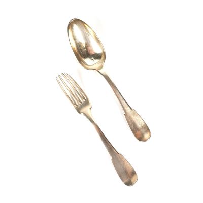 deux cuillères et une fourchette en argent sur une surface blanche