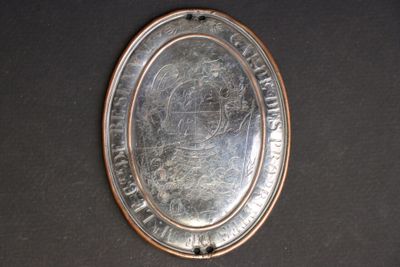 a silver plate with a picture on it on a table