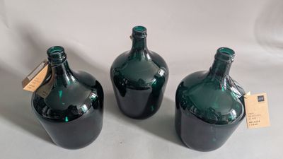 three green glass bottles sitting on top of a white table