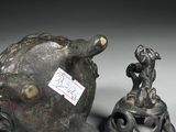 two bronze figurines of animals and a bell on a table