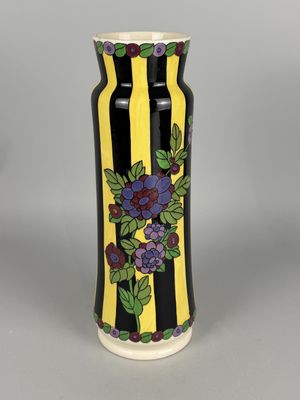yellow and black striped vase with purple flowers and green leaves
