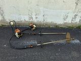 two lawn mowers on the ground next to a wall