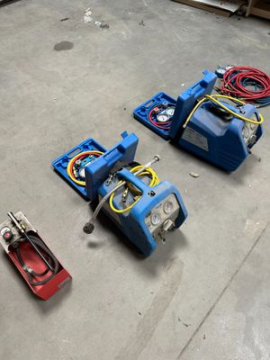 deux outils pneumatiques posés par terre à côté d'une boîte à outils