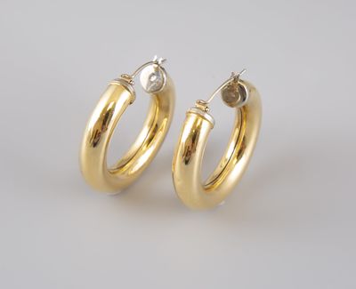 une paire de boucles d'oreilles en or sur fond blanc