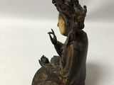 a bronze statue of a woman sitting on a rock with a bird in her hand