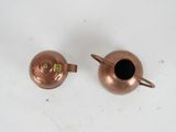 two small copper pots on a white table