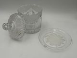 a glass container with a lid sitting next to a glass plate