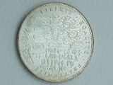 a silver coin that is on a white surface