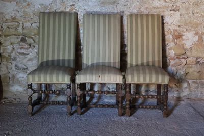 three chairs sitting next to each other in front of a stone wall