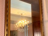 a mirror hanging on the wall with a chandelier in the background