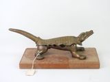 bronze sculpture of a lizard on a wooden base with a tag