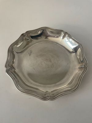 une assiette en argent posée sur une table, sur fond blanc