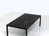 La table est en marbre noir et possède une structure en métal noir.