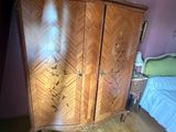 une armoire en bois dans un coin d'une chambre où se trouve un lit