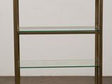 a brass and glass bookcase on a wooden floor