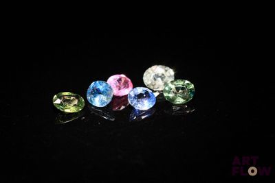 a close up of a group of different colored gems on a black surface