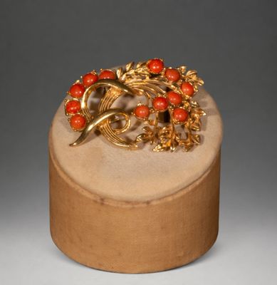 a gold and red brooch on top of a wooden box