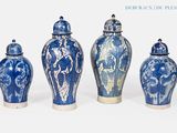quatre vases bleus et blancs sont alignés sur un fond blanc