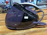 a black and white steam iron sitting on a wooden table