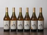 six bottles of wine are lined up on a table in front of a white wall