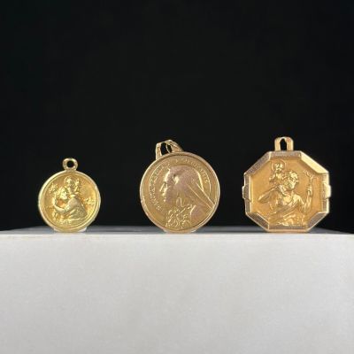 trois médailles d'or sont posées sur une surface blanche