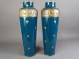 une paire de vases bleus ornés de motifs dorés sur fond gris