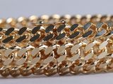 a close up of a gold bracelet on a white surface